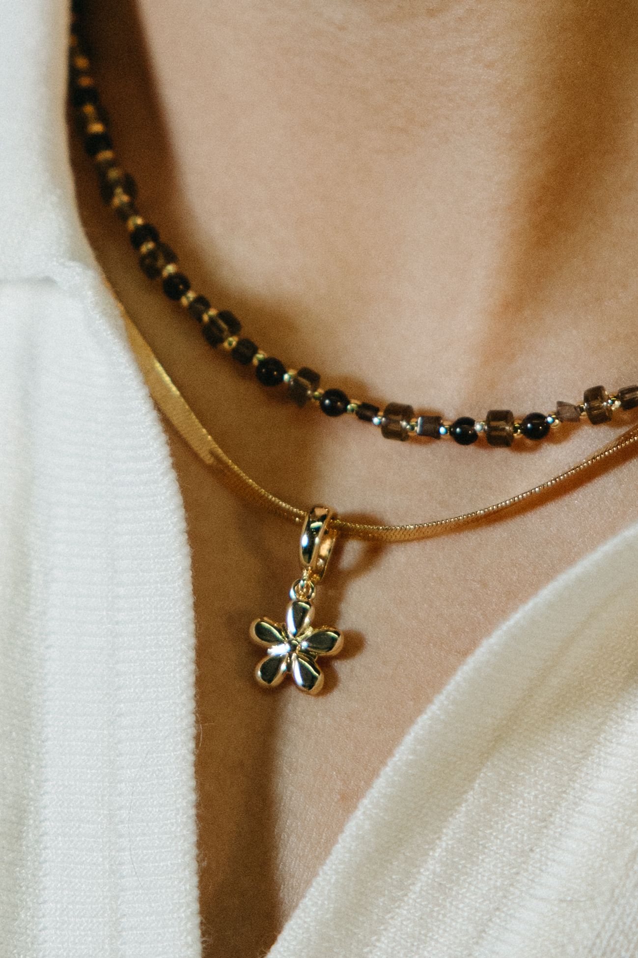 Close-up view of a delicate gold necklace with a small butterfly pendant on a white background.