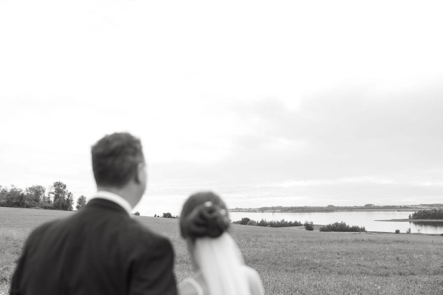 Newlyweds gaze at the waterfront landscape together during their wedding photoshoot.