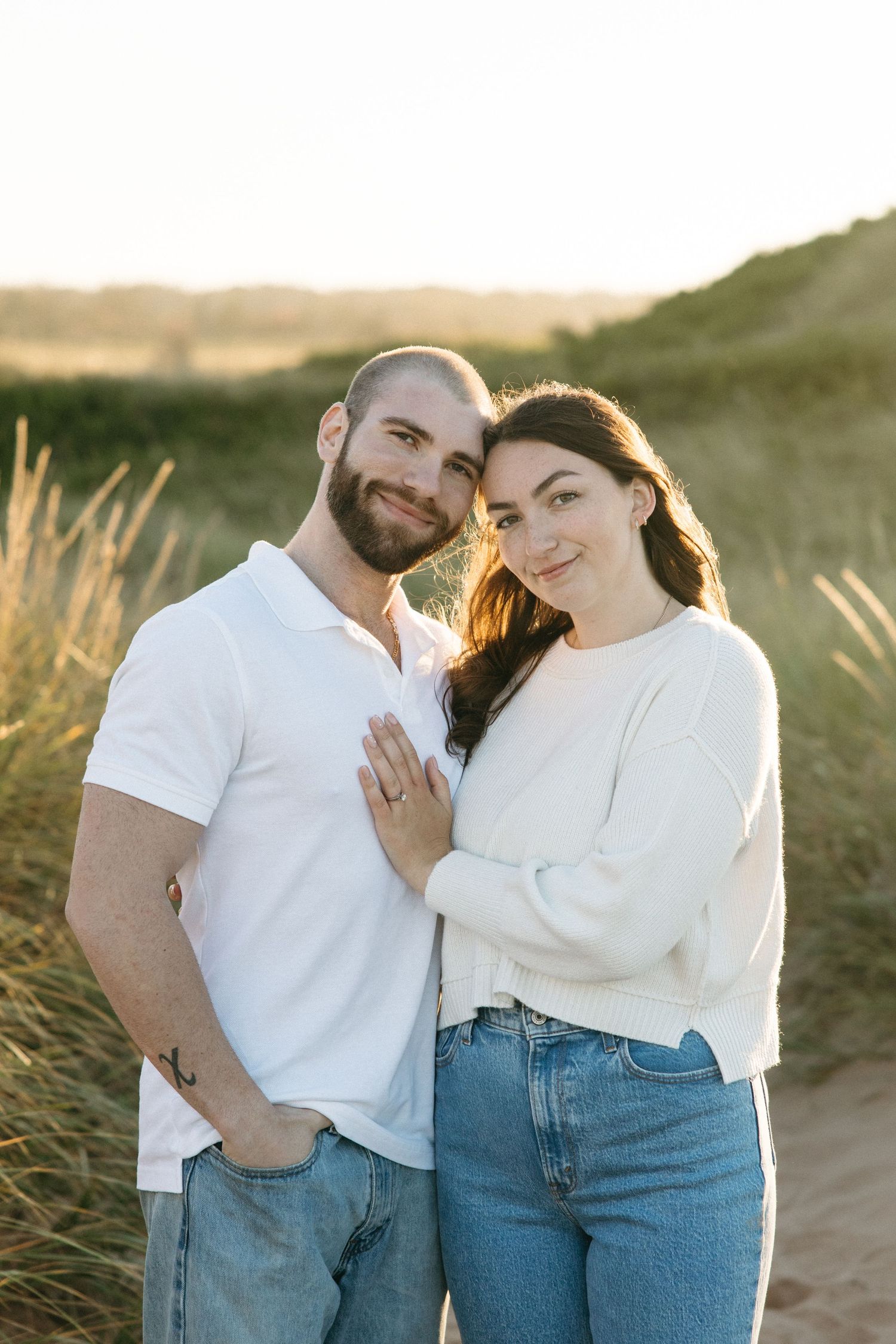 Couple in white and denim sharing affectionate moments against natural scenery.