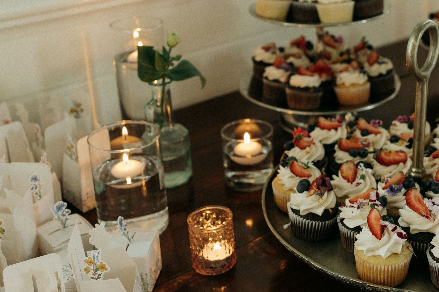Elegant wedding dessert display featuring cupcakes and candles on tiered stands.