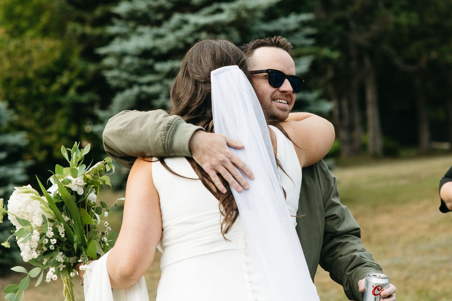 An emotional embrace between two people at an outdoor wedding celebration.
