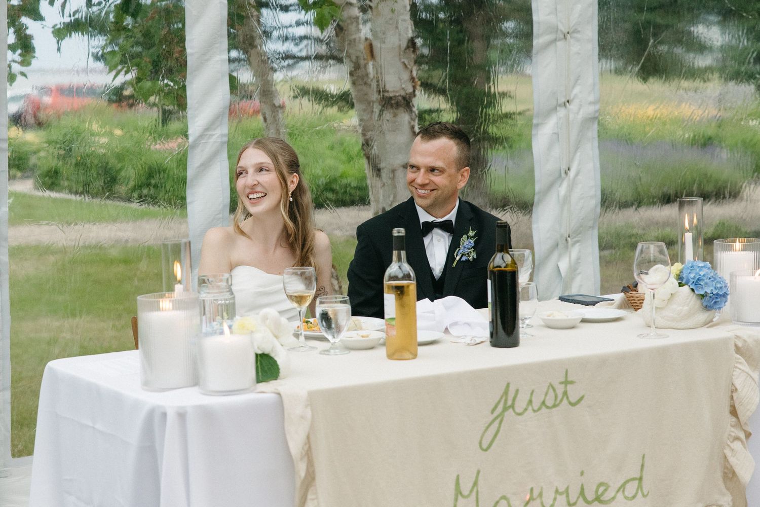 Bride and groom smiling at sweetheart table with Just Married sign.