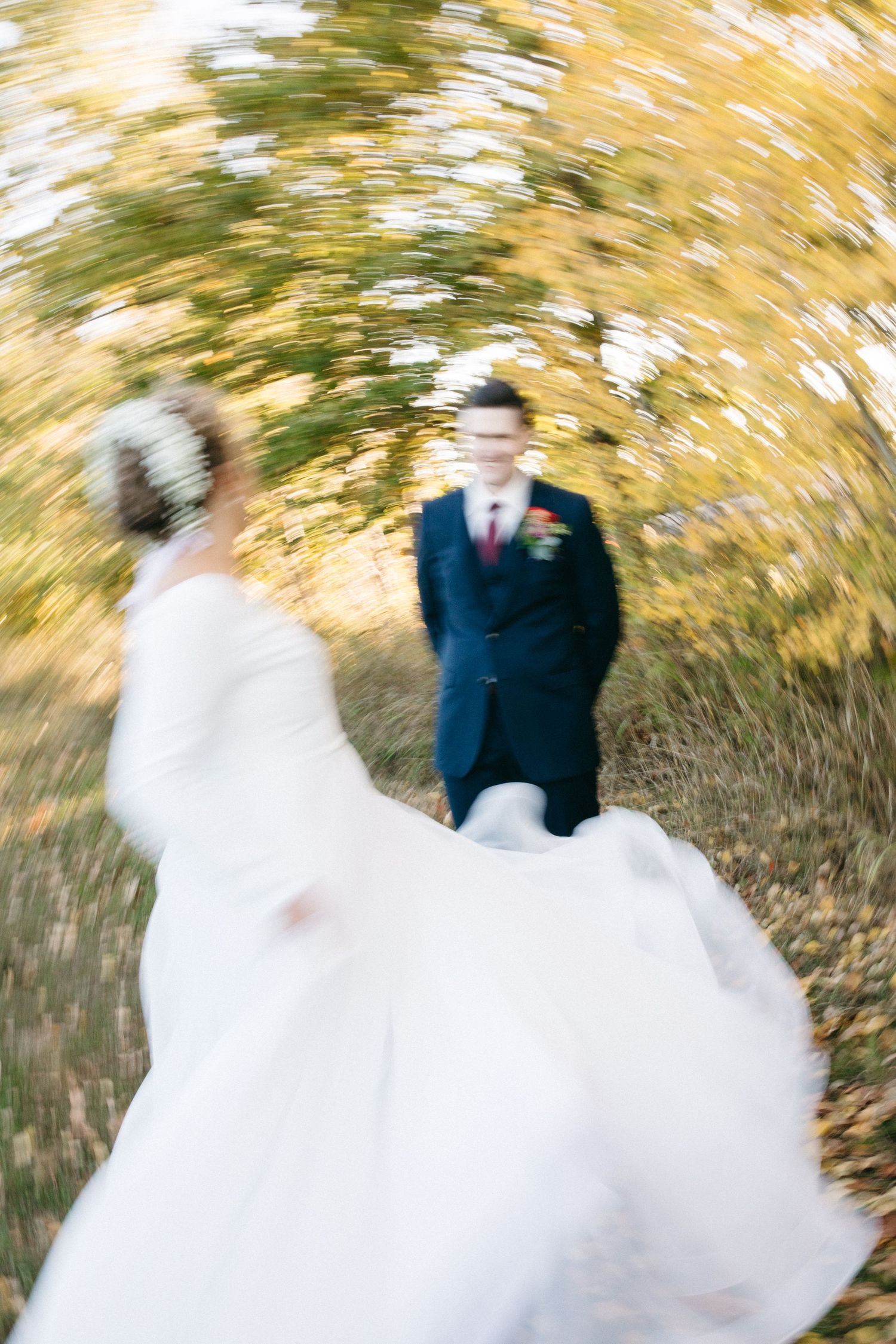 Creative motion blur wedding photo with spinning couple against autumn trees.