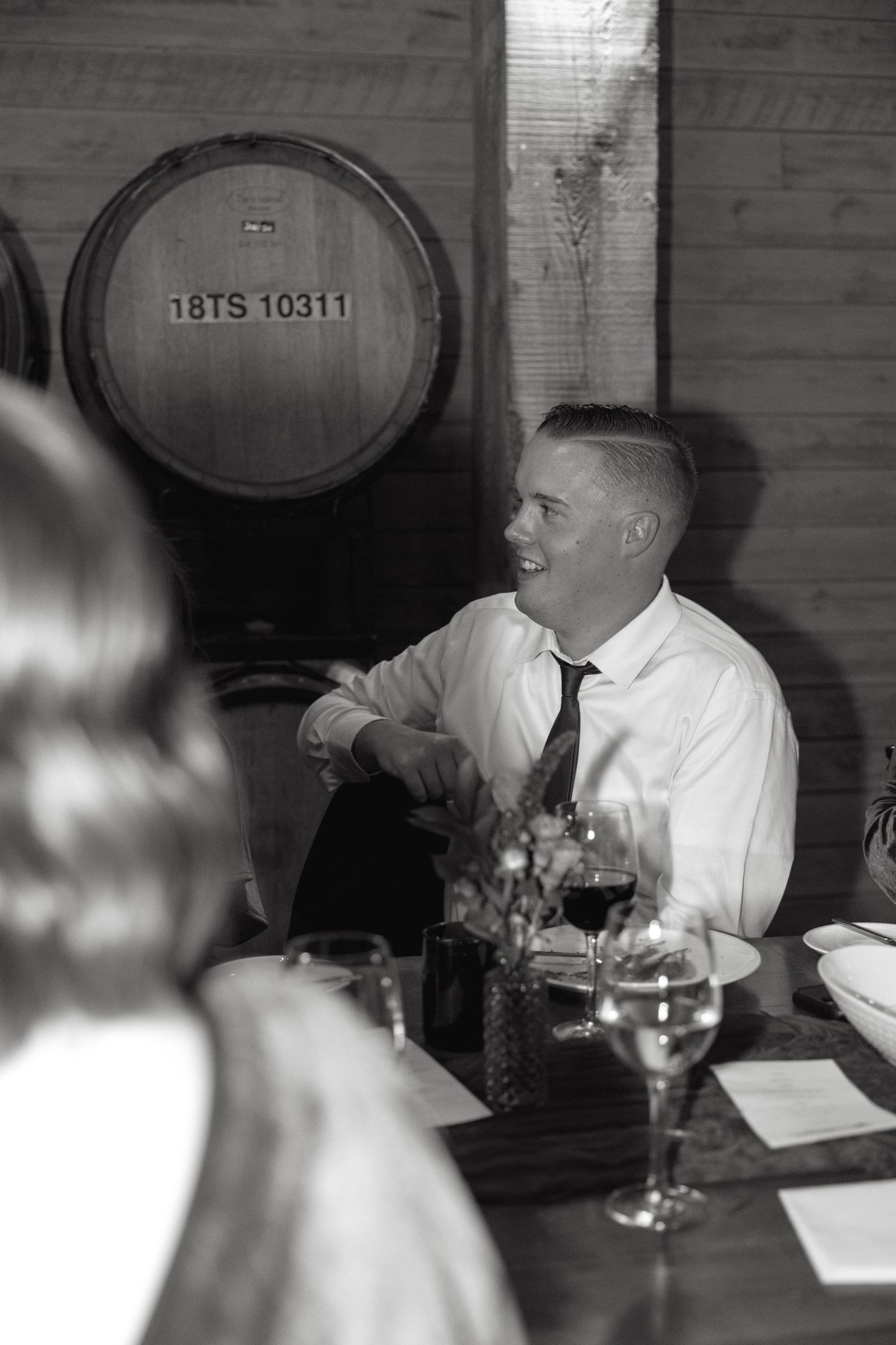 Wine barrels line the wall of a rustic cellar during an intimate dinner gathering.