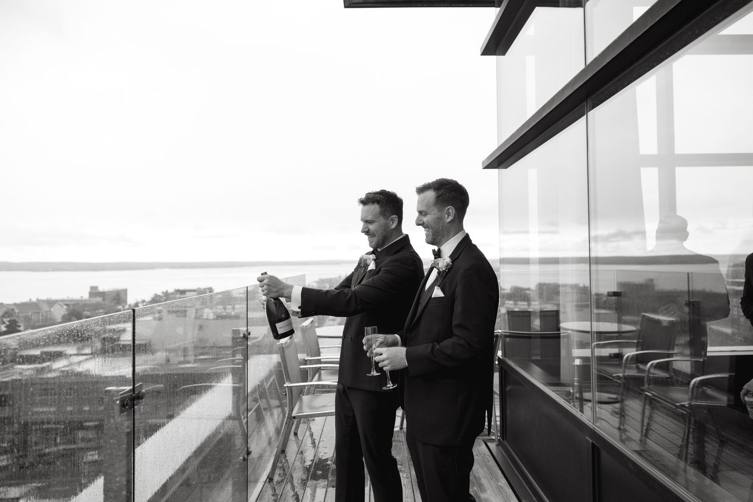 People in formal attire stand together on a rooftop overlooking a city skyline.