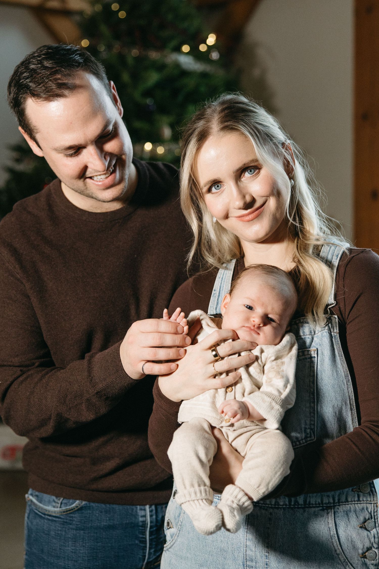 Sweet candid moments of a family sharing smiles and cuddles near a lit Christmas tree.