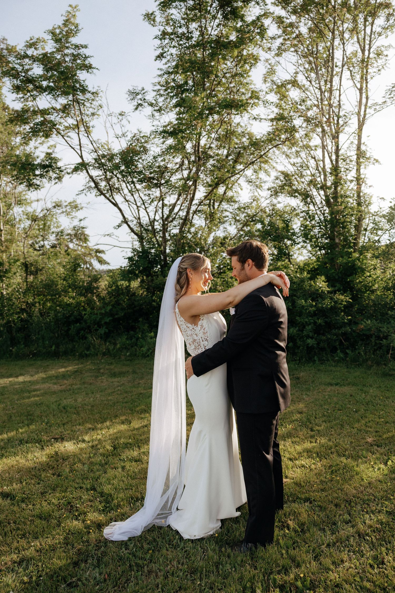 A couple shares an intimate first look moment outdoors on their wedding day in a grassy field.