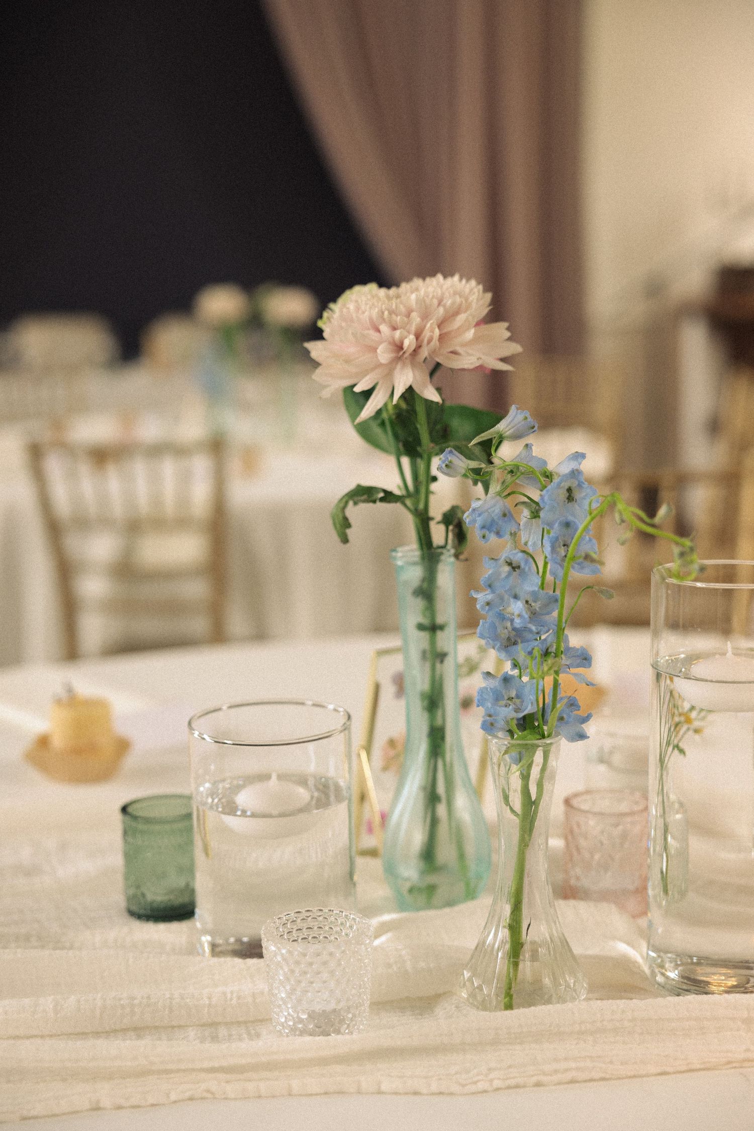 Elegant table settings with blue and pink flowers in vintage glass vases.