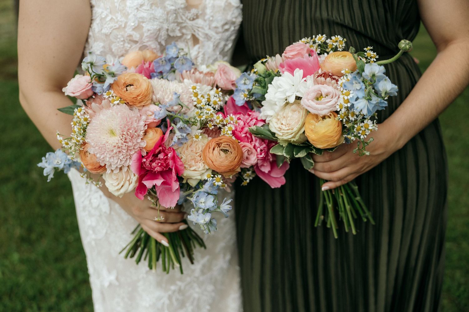 Colorful wedding bouquets featuring pink, peach and blue flowers against dark dresses.