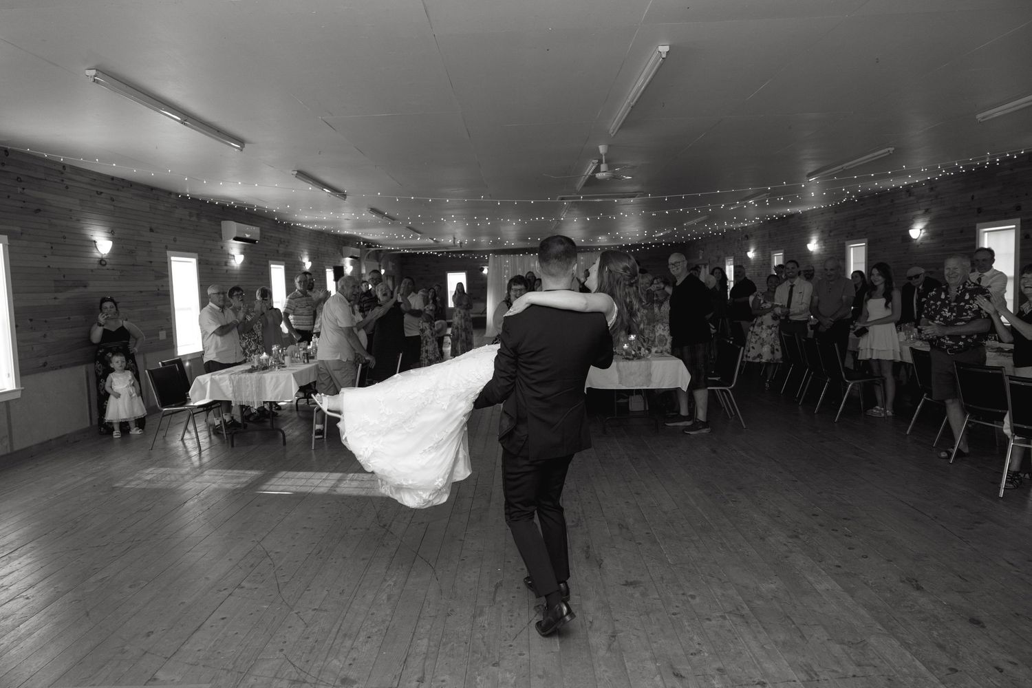 Wide-angle view of dimly lit reception hall with guests dancing.
