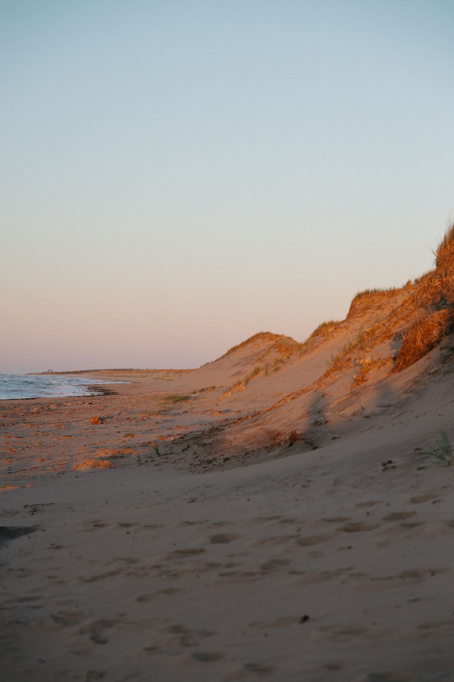 Sandy beach dunes glowing orange in the warm evening sunlight.