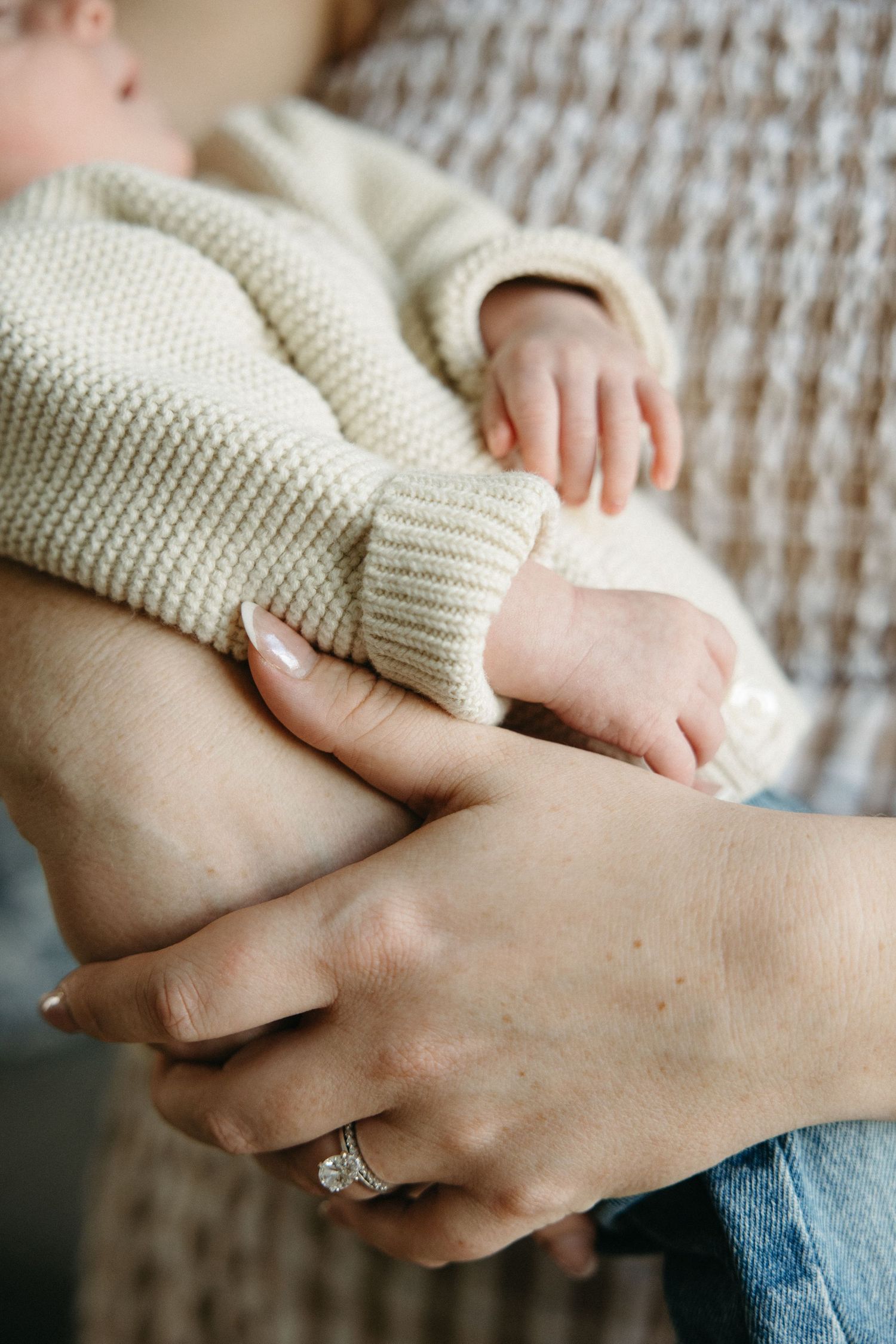 Hands in a cream knit sweater gently embrace in a tender moment.