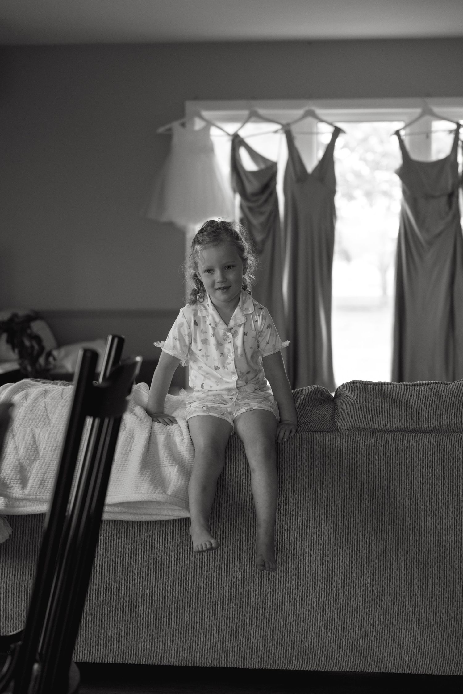 Black and white photo of children peeking over a couch back.