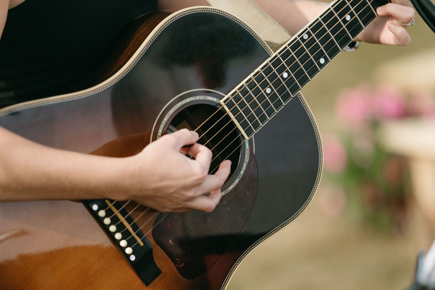 Close-up details of acoustic guitar being played at outdoor event.
