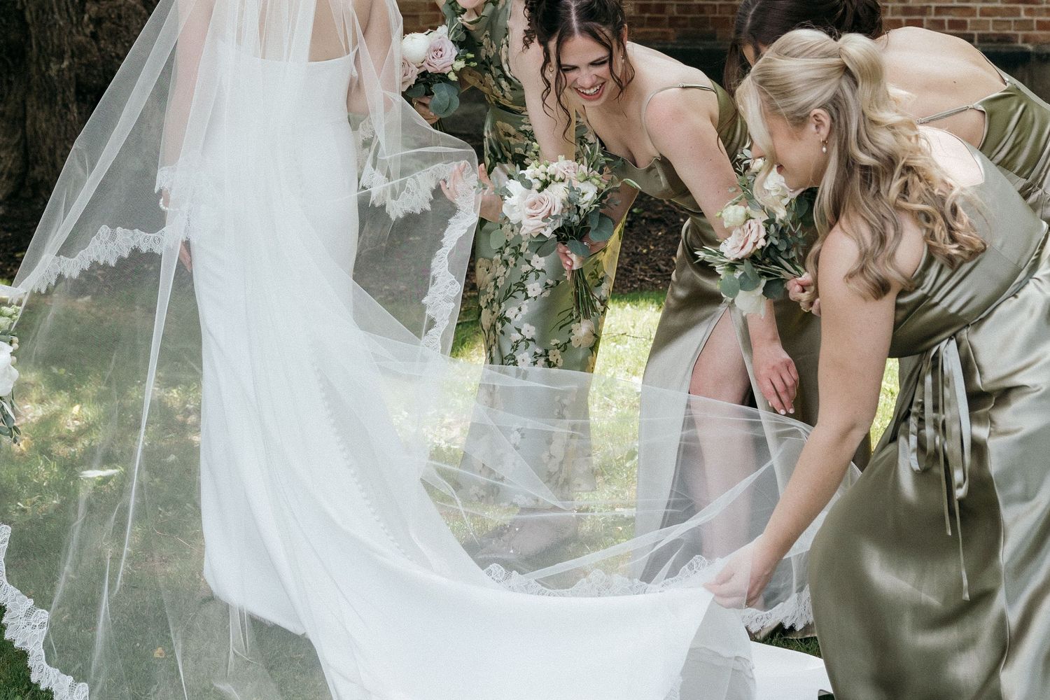 Close-up view of wedding party members holding white and green bouquets.