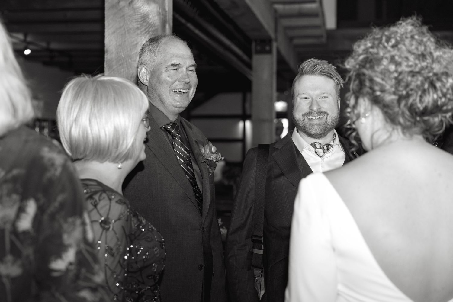 Wedding reception guests mingling in a rustic venue with string lights.