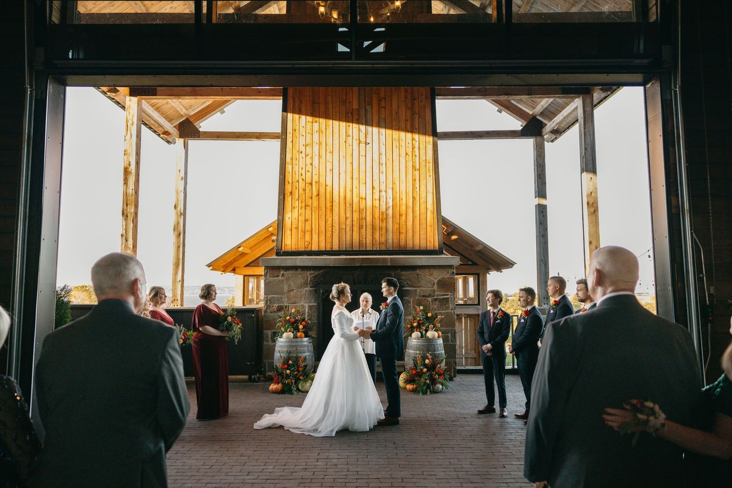 Wide-angle view of a wedding ceremony in a rustic barn with natural lighting.