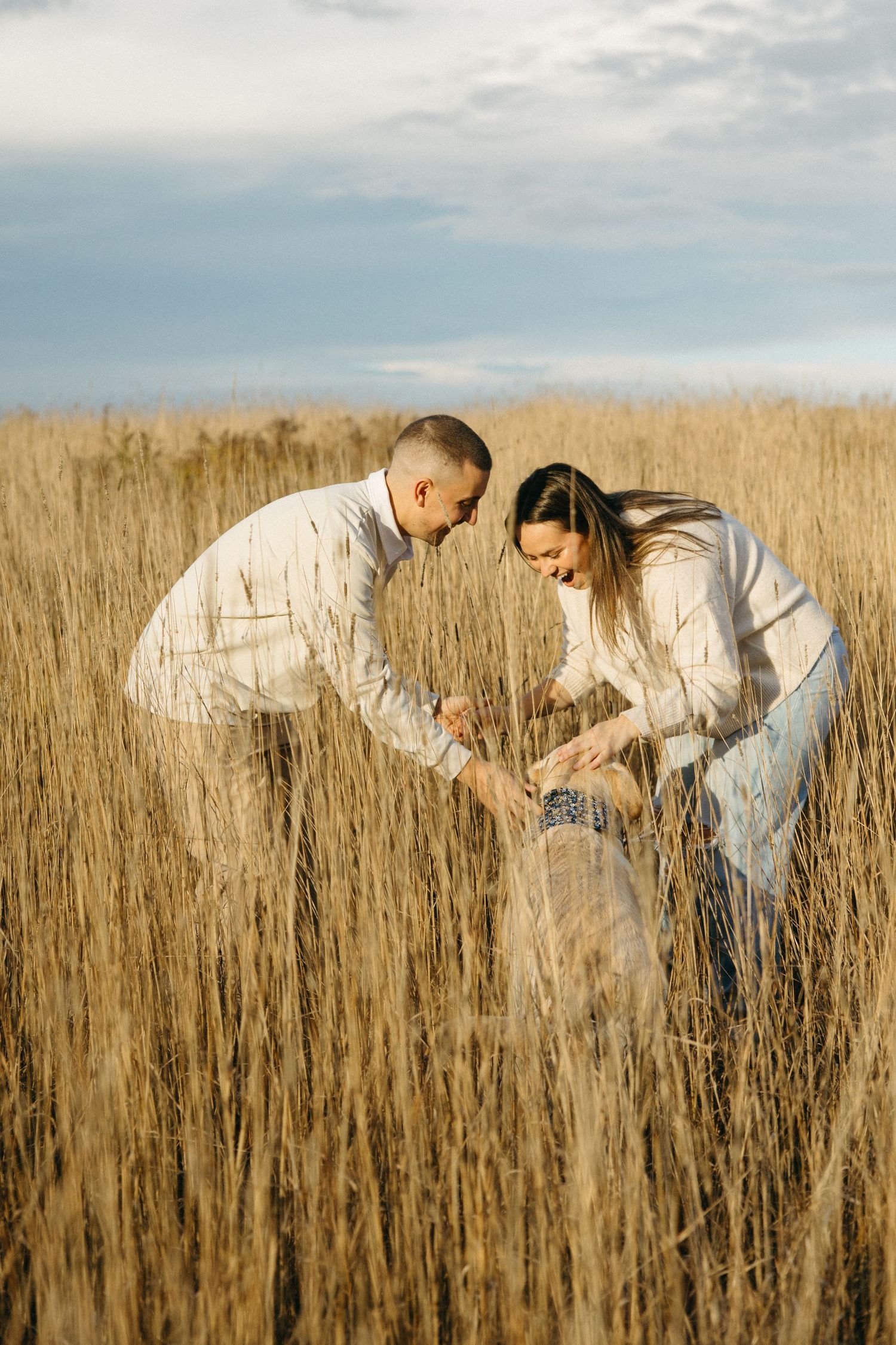 Two people playing and laughing together in a golden wheat field.