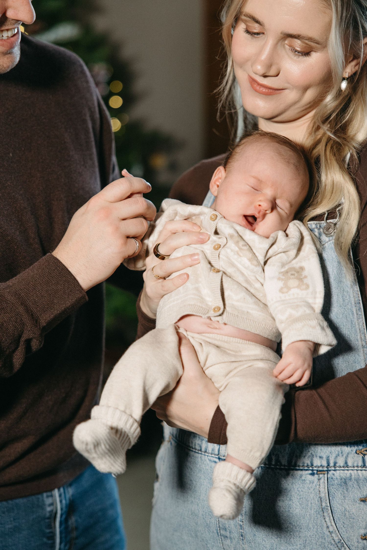 Gentle moments captured between parents and baby in front of holiday decorations.