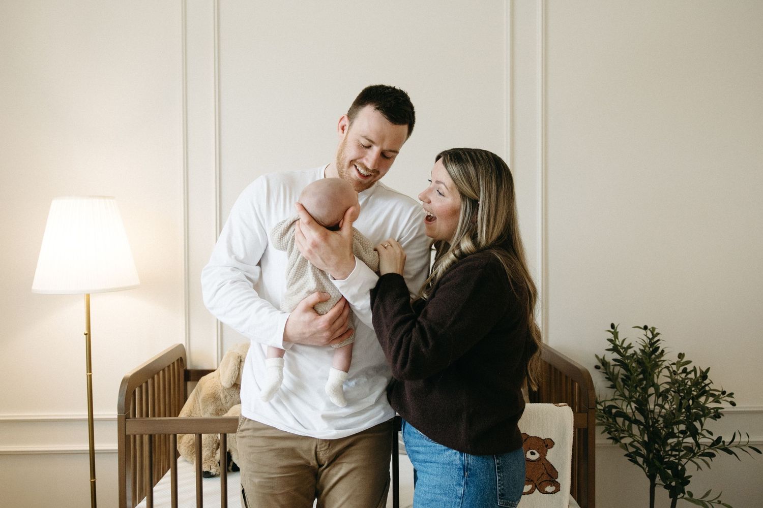 A sweet family scene in a modern nursery with wooden furniture and warm lighting.