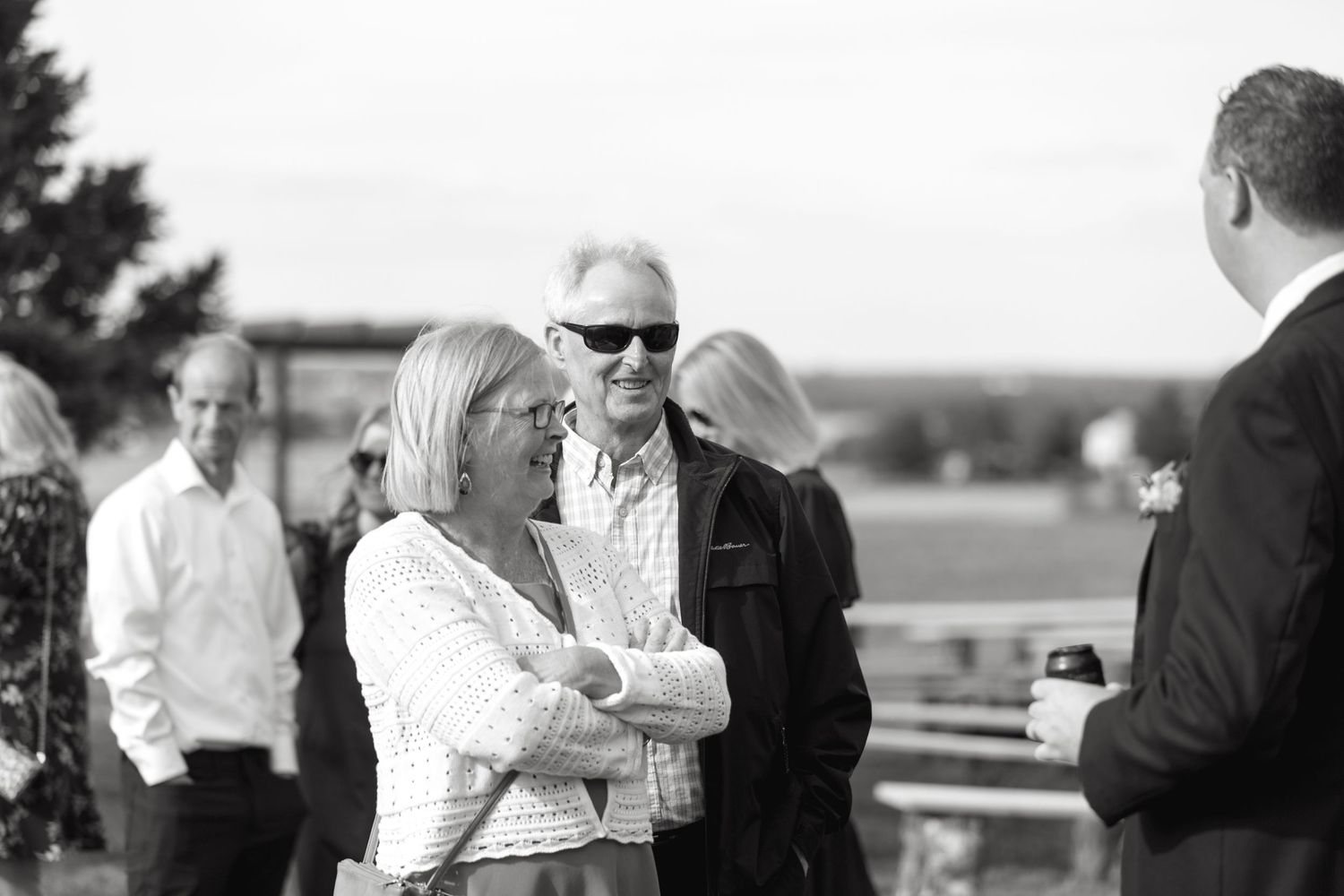 Black and white photos of guests mingling at outdoor wedding reception.