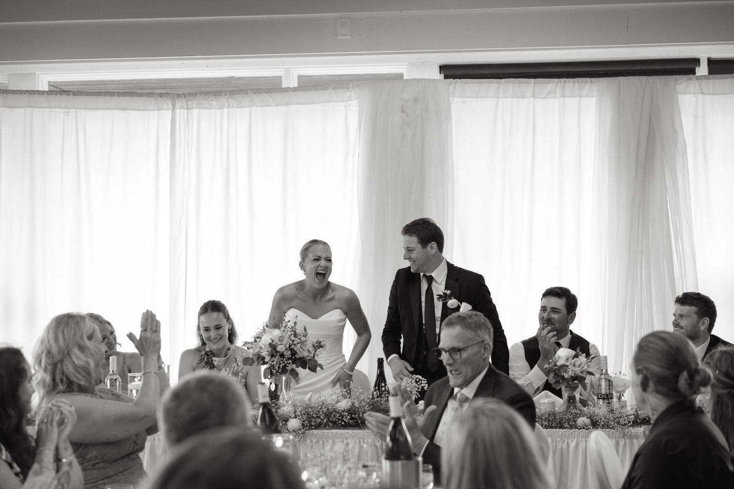 Wedding reception guests celebrating and interacting in bright indoor venue.