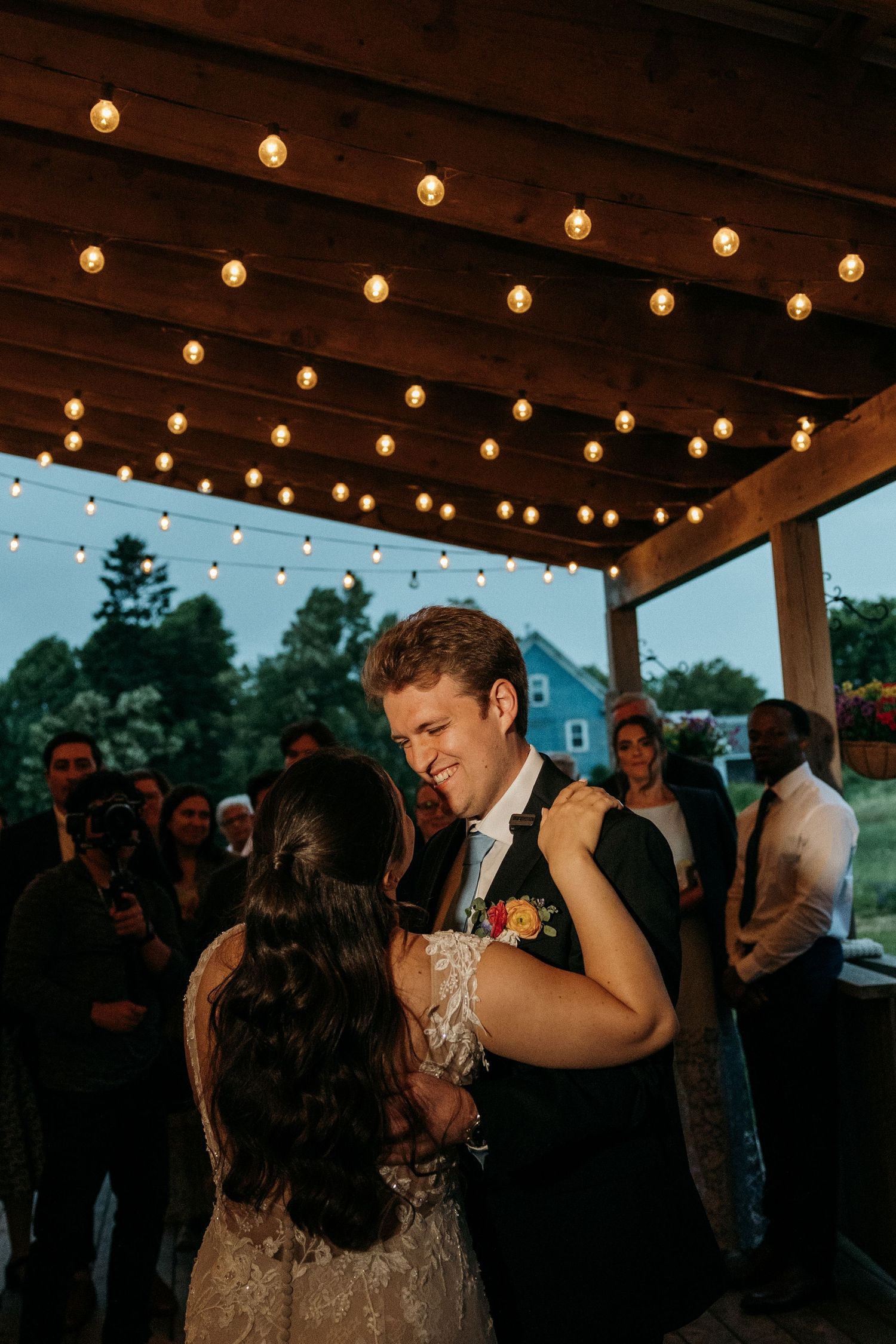 Couple sharing an intimate dance under string lights at dusk.