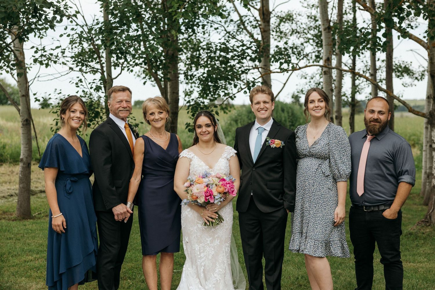 Wedding party group photos taken in a wooded outdoor setting.