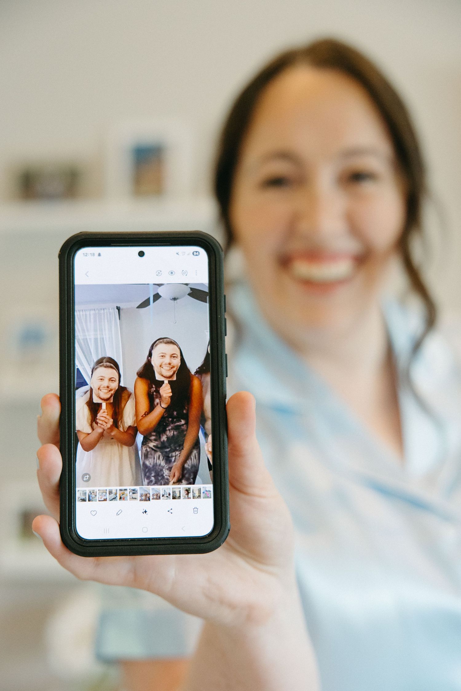 Hand holding phone displaying photos in bright interior setting.