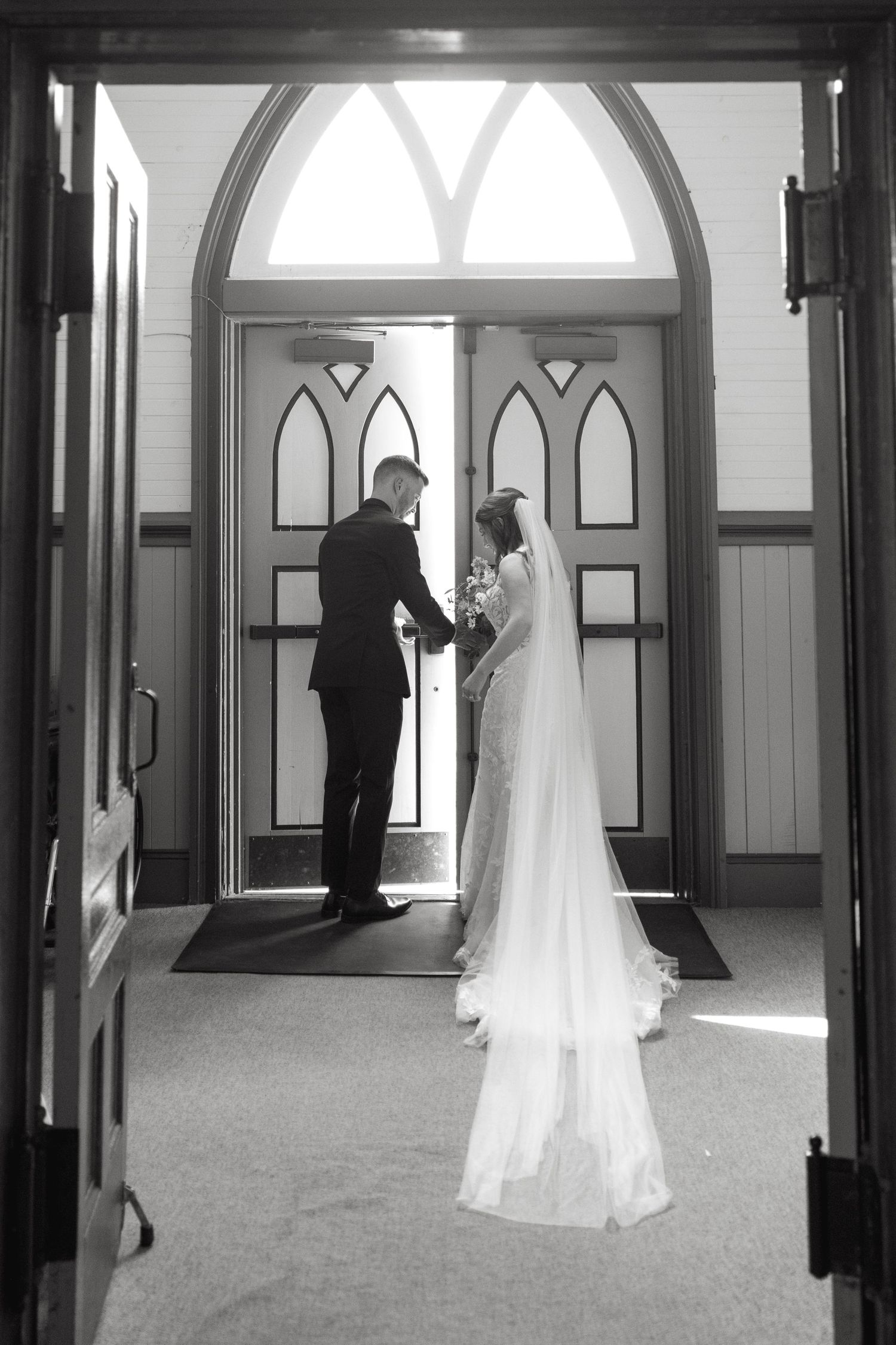 Wedding dresses displayed in elegant hallway with arched windows and white walls.