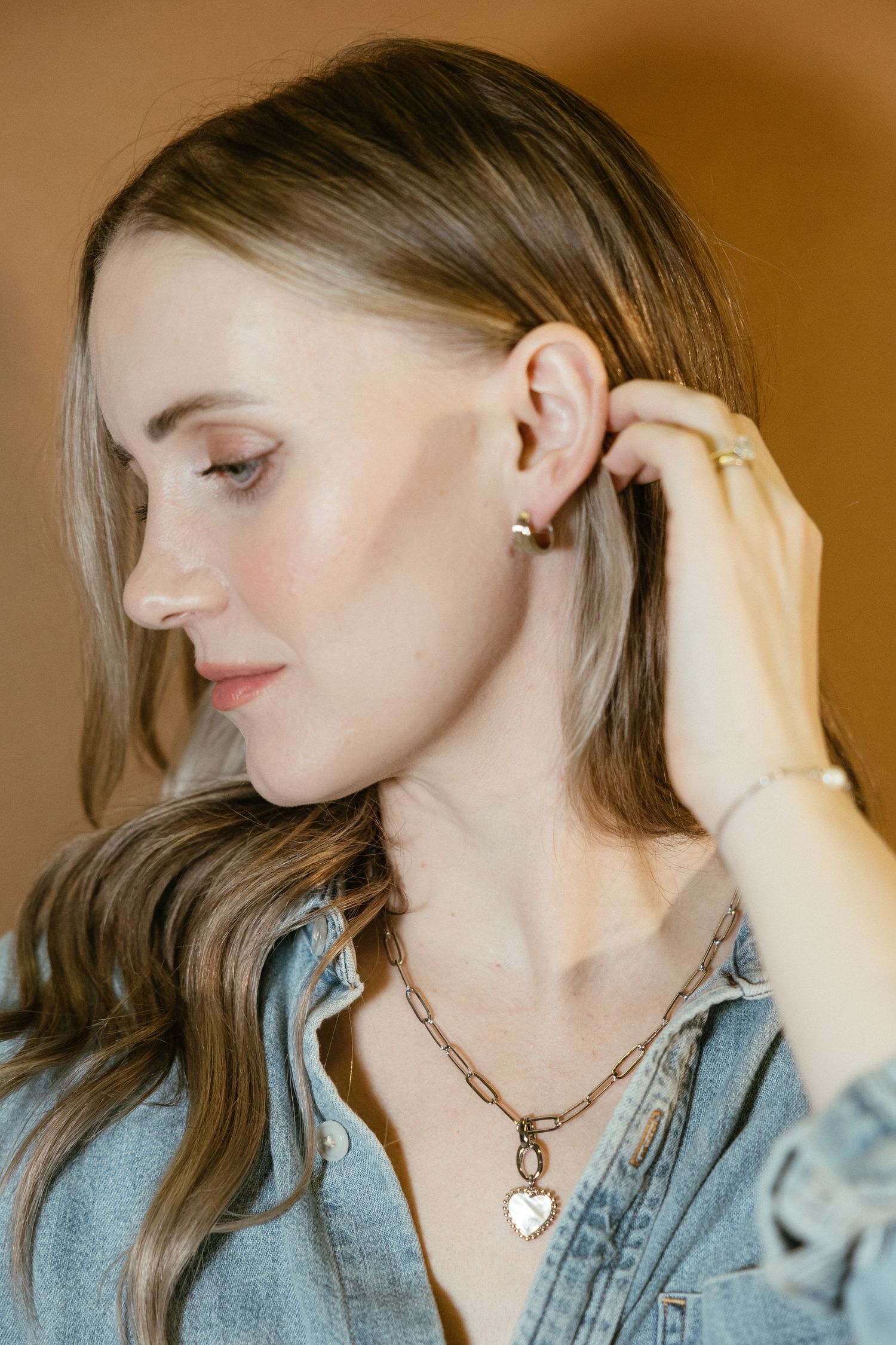 Elegant necklace with heart pendant shown on model wearing denim jacket.