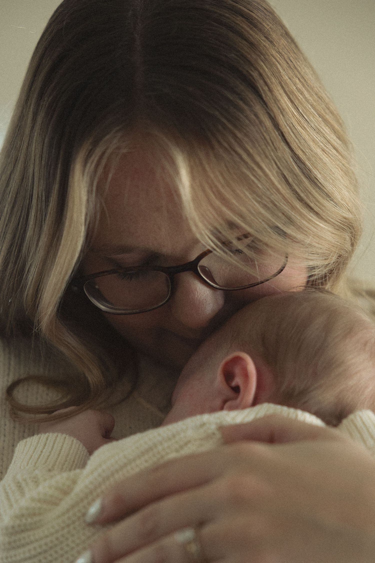 Series of intimate moments showing parent cuddling with infant in soft light.