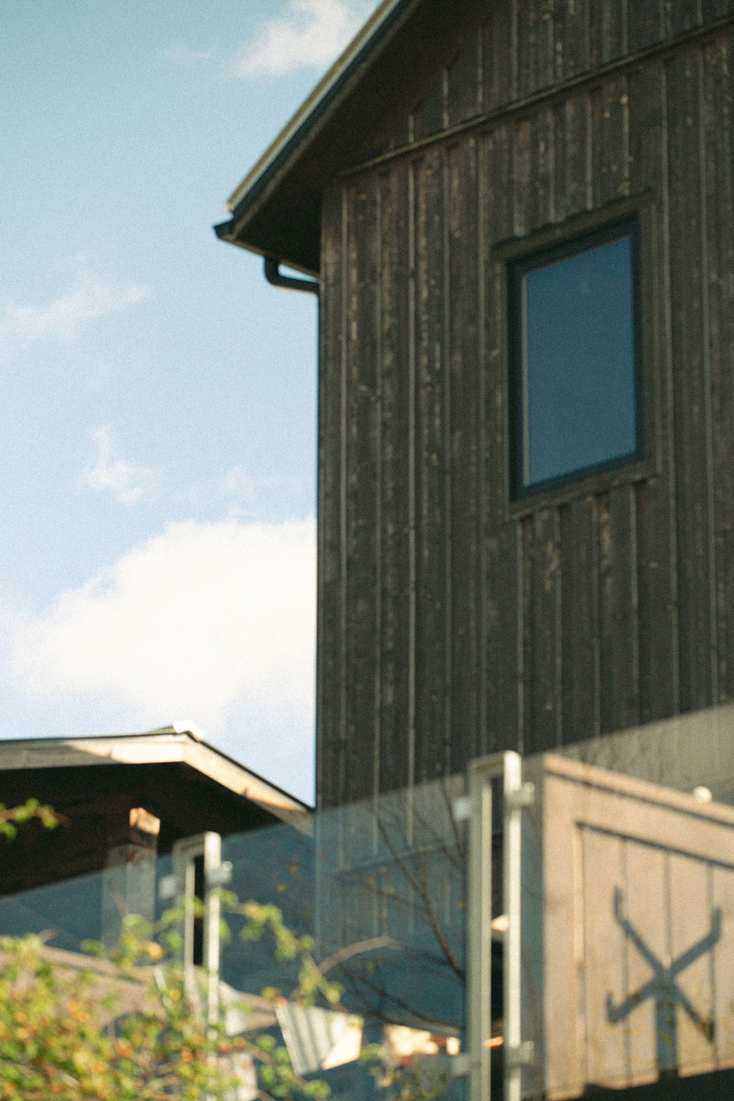 Rustic wooden barn exterior with blue window against cloudy sky.