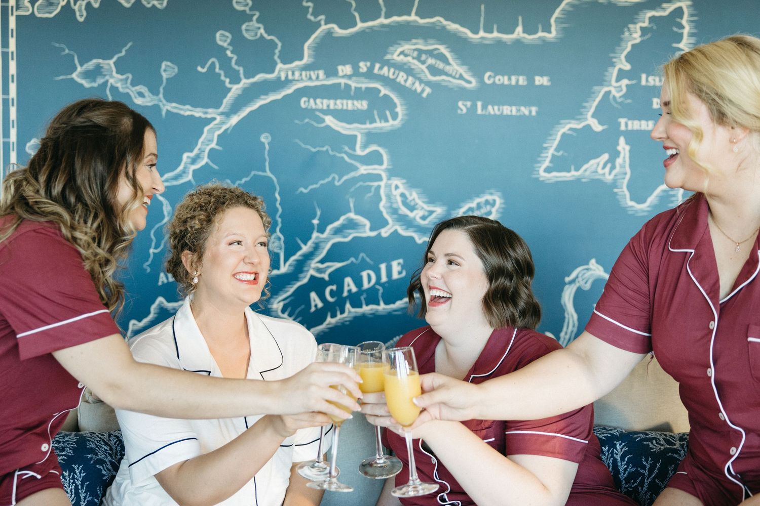Friends in burgundy and white outfits share laughs while holding beverages.