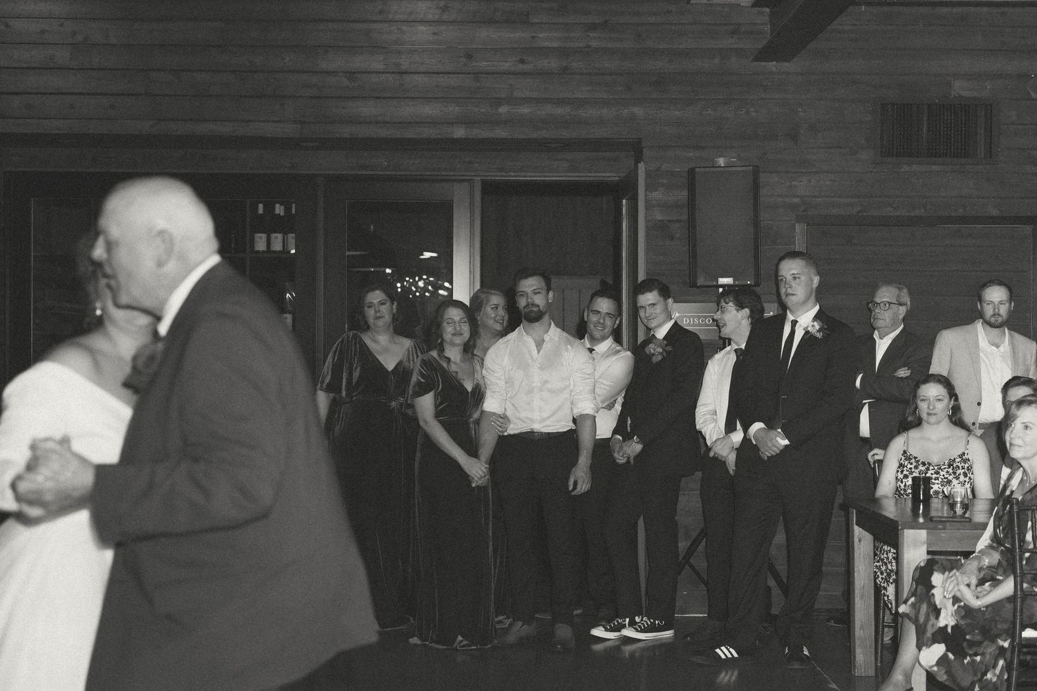 Wedding reception guests dancing and celebrating on a wooden dance floor.