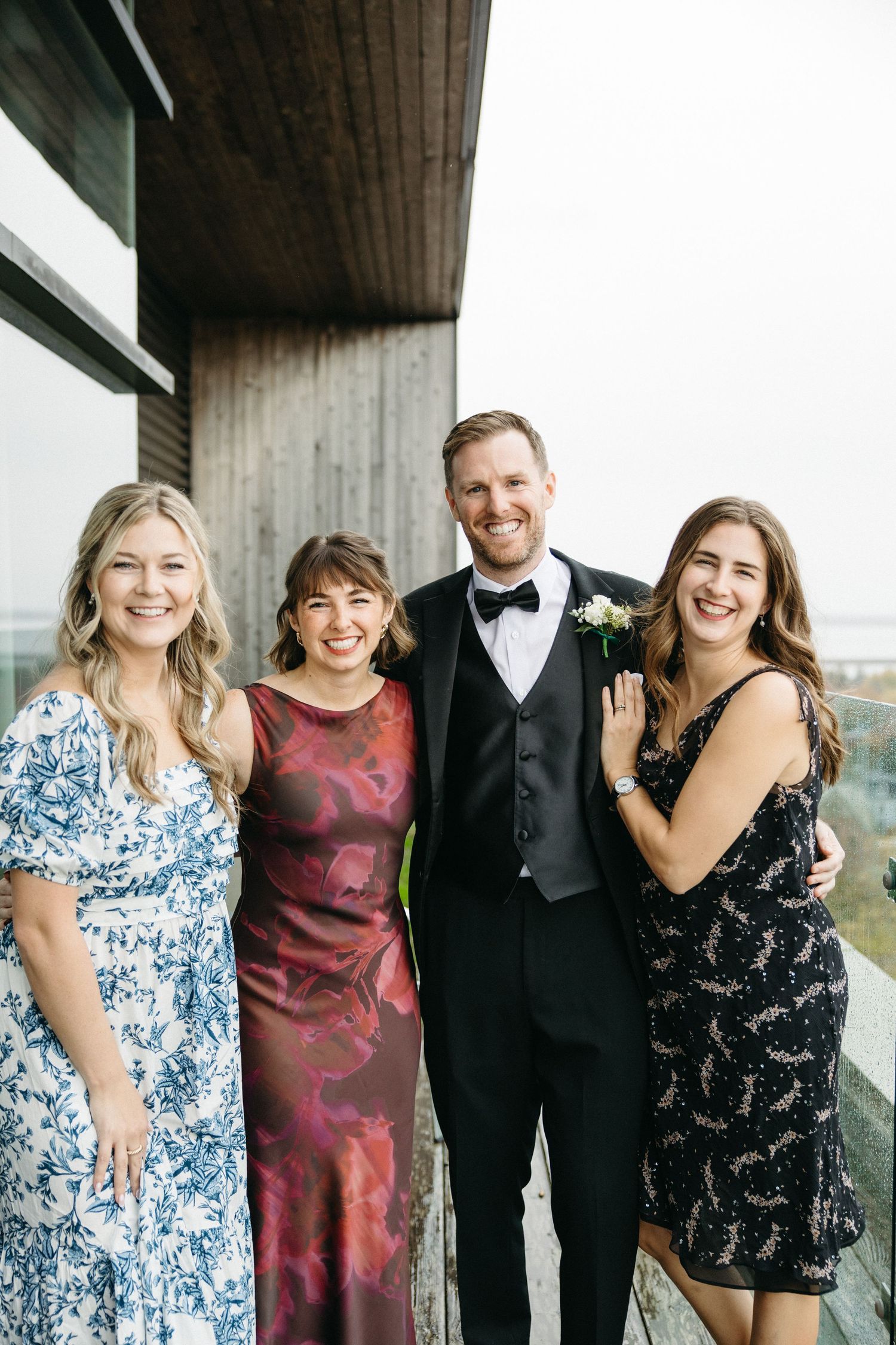 Wedding party members pose together on a balcony in formal attire.