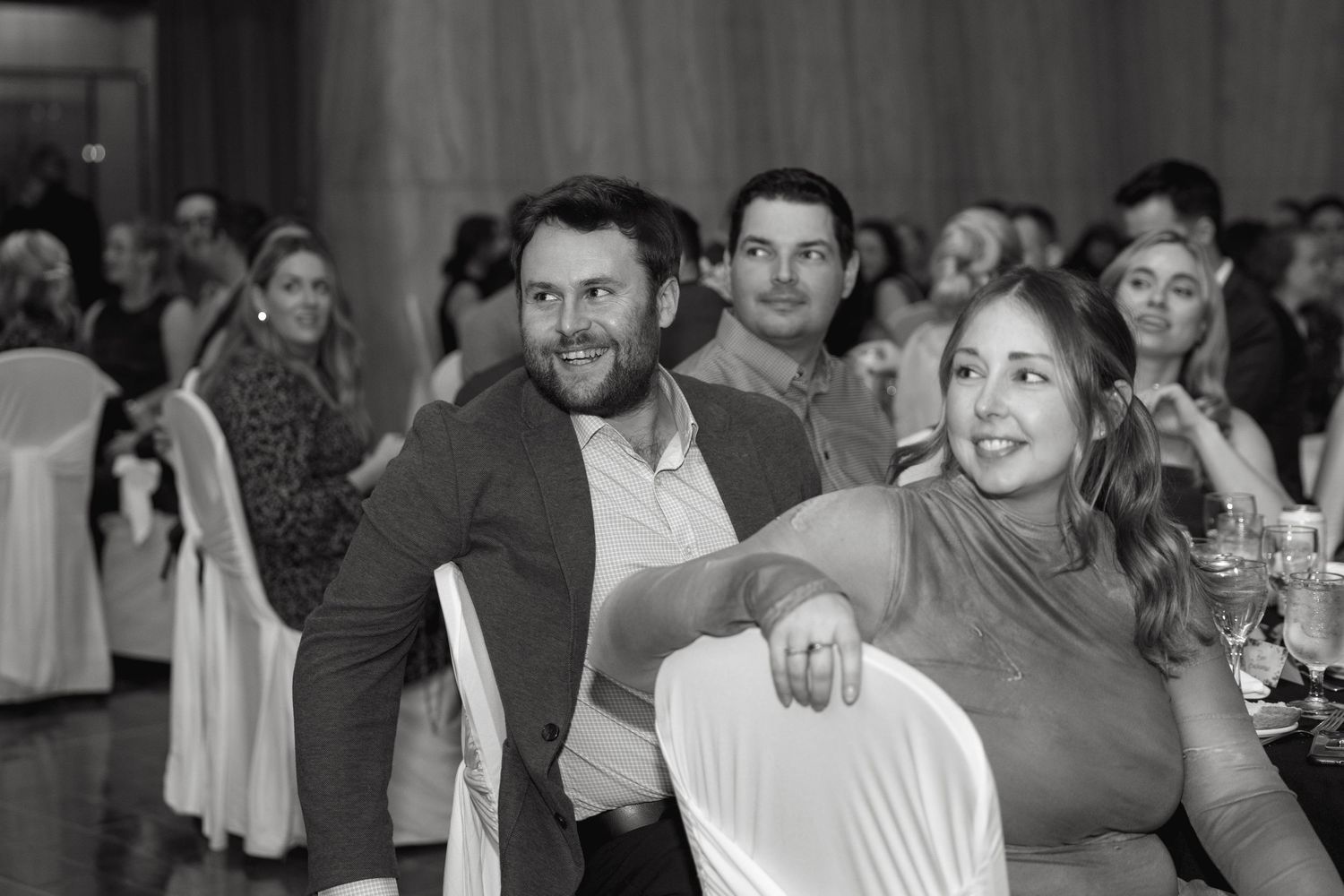 Black and white photo of wedding guests enjoying themselves at a reception.