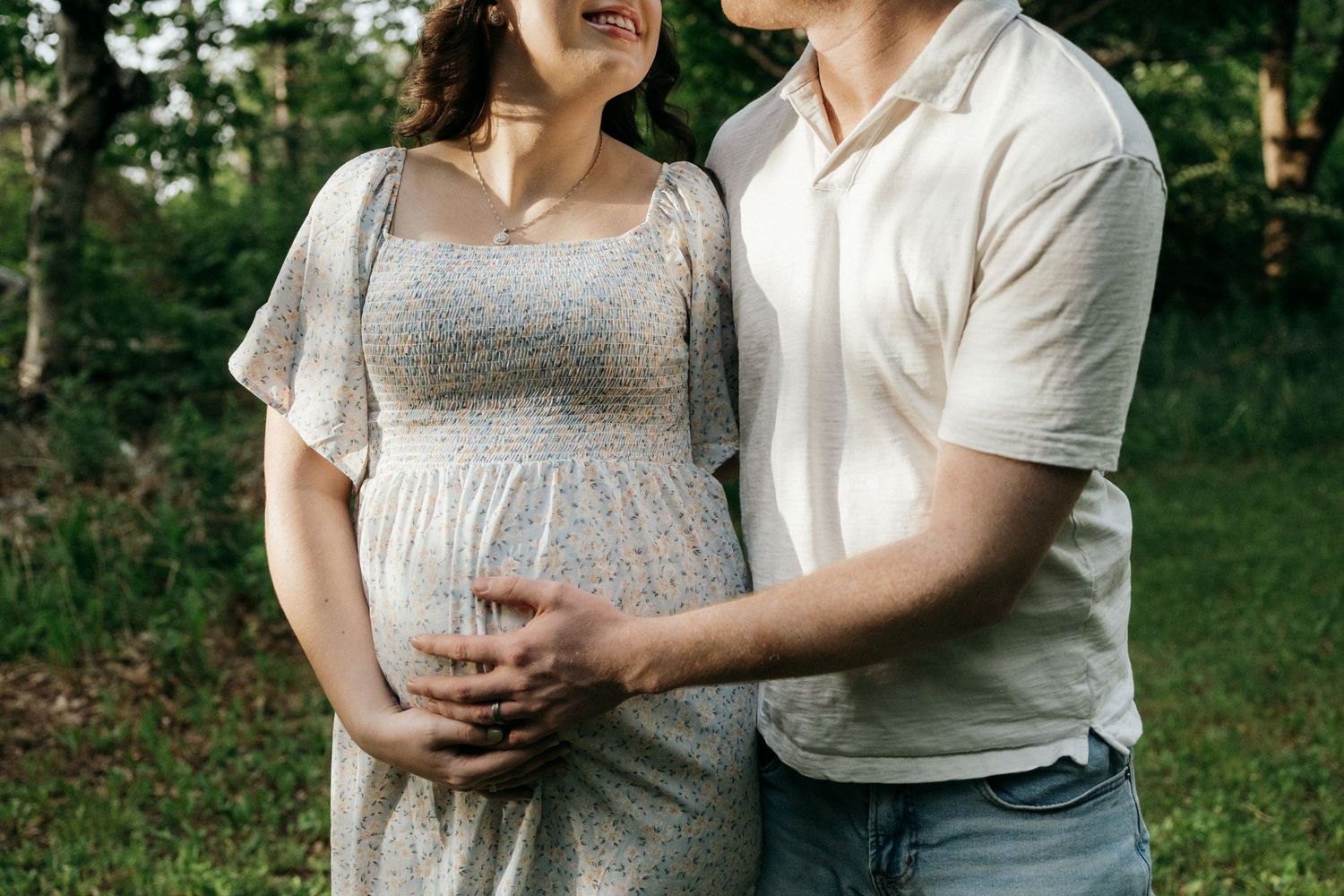 Close-up shot of a couple in casual attire standing together in a park setting.