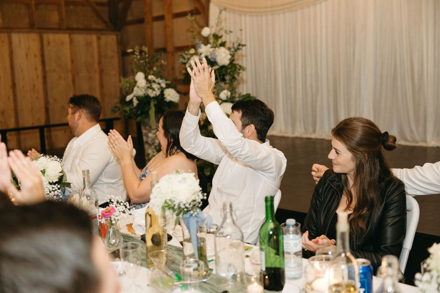 Wedding guests celebrate with raised hands during reception party.