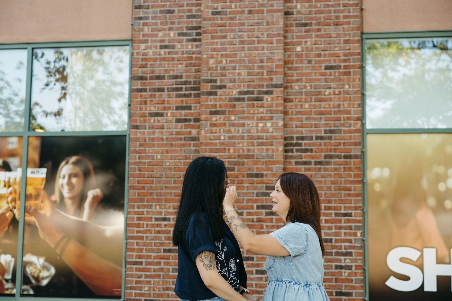 Friends enjoying beverages together at an outdoor seating area with brick building backdrop.