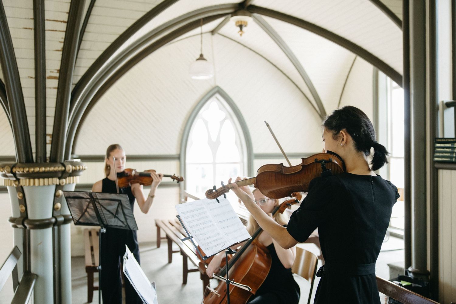 String musicians perform in an elegant church with vaulted gothic arches.