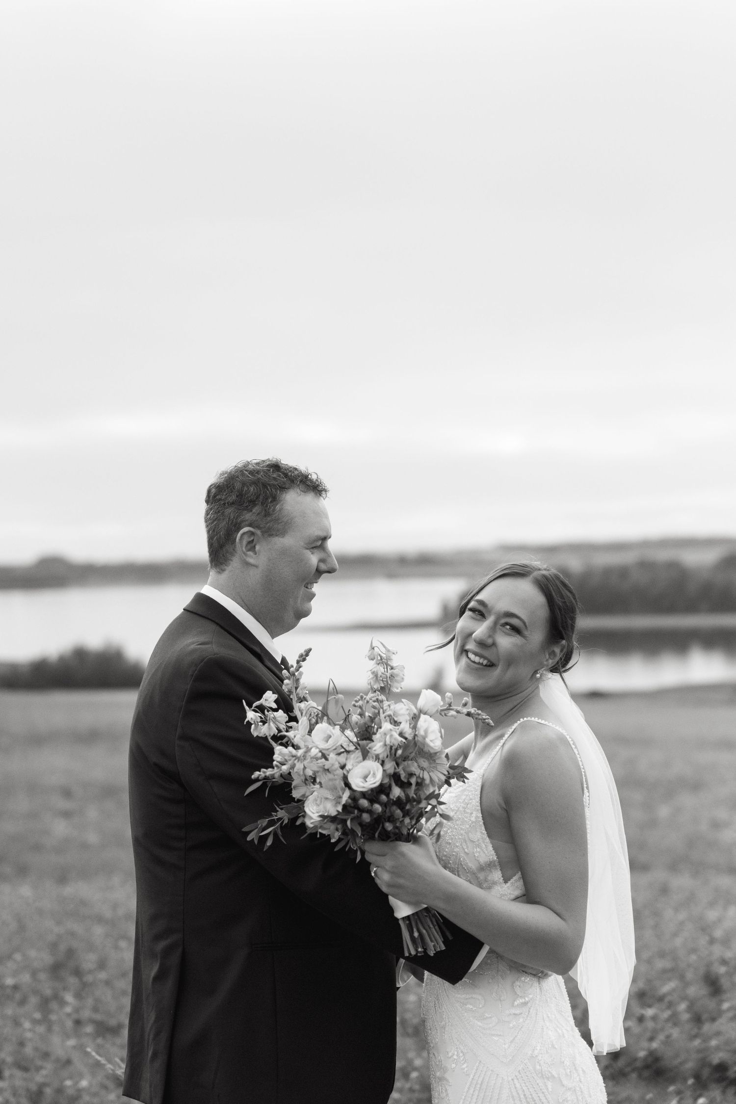 Romantic wedding moment captured in black and white on an open field.