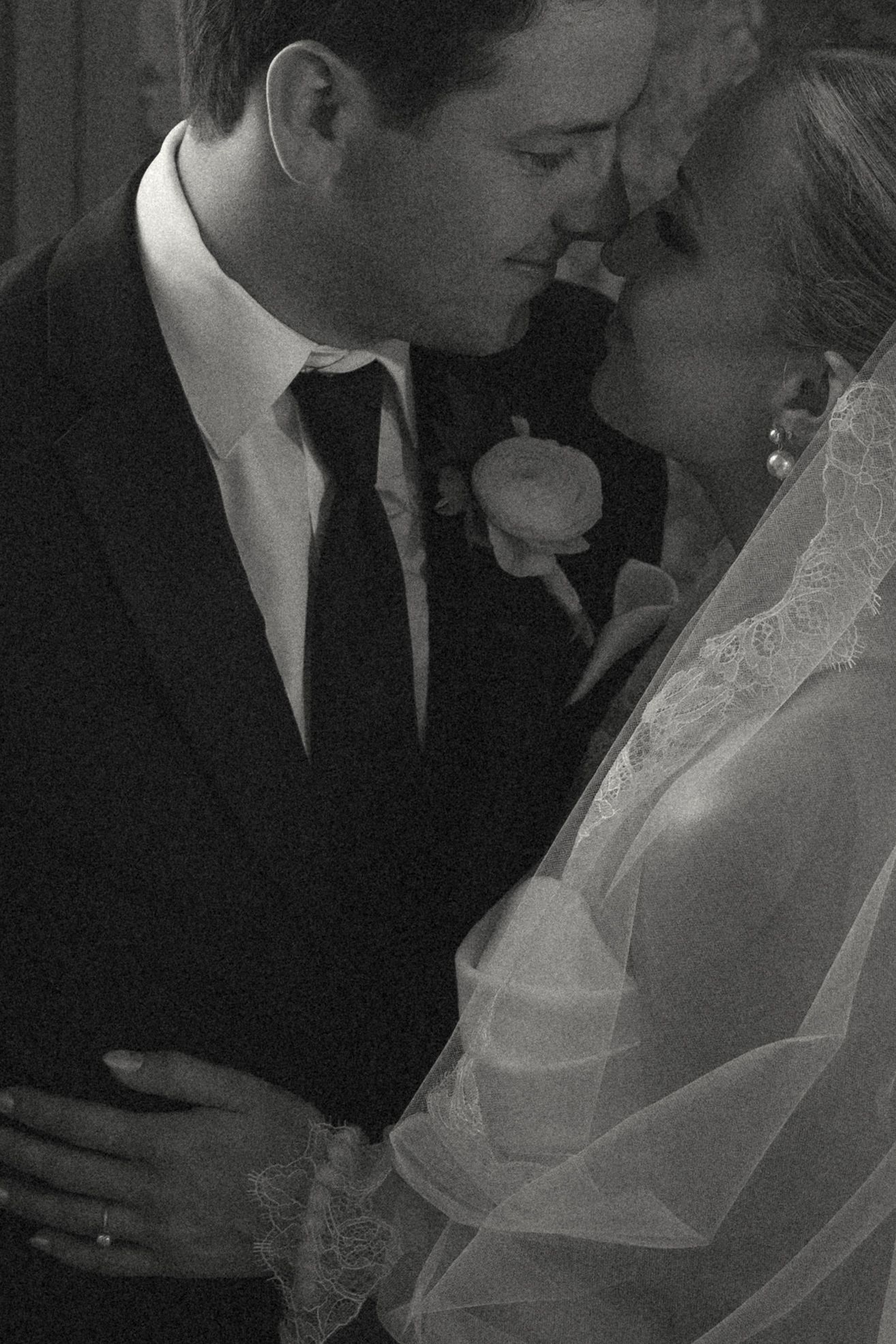 Black and white romantic wedding portrait showing tender moment between newlyweds in formal attire.