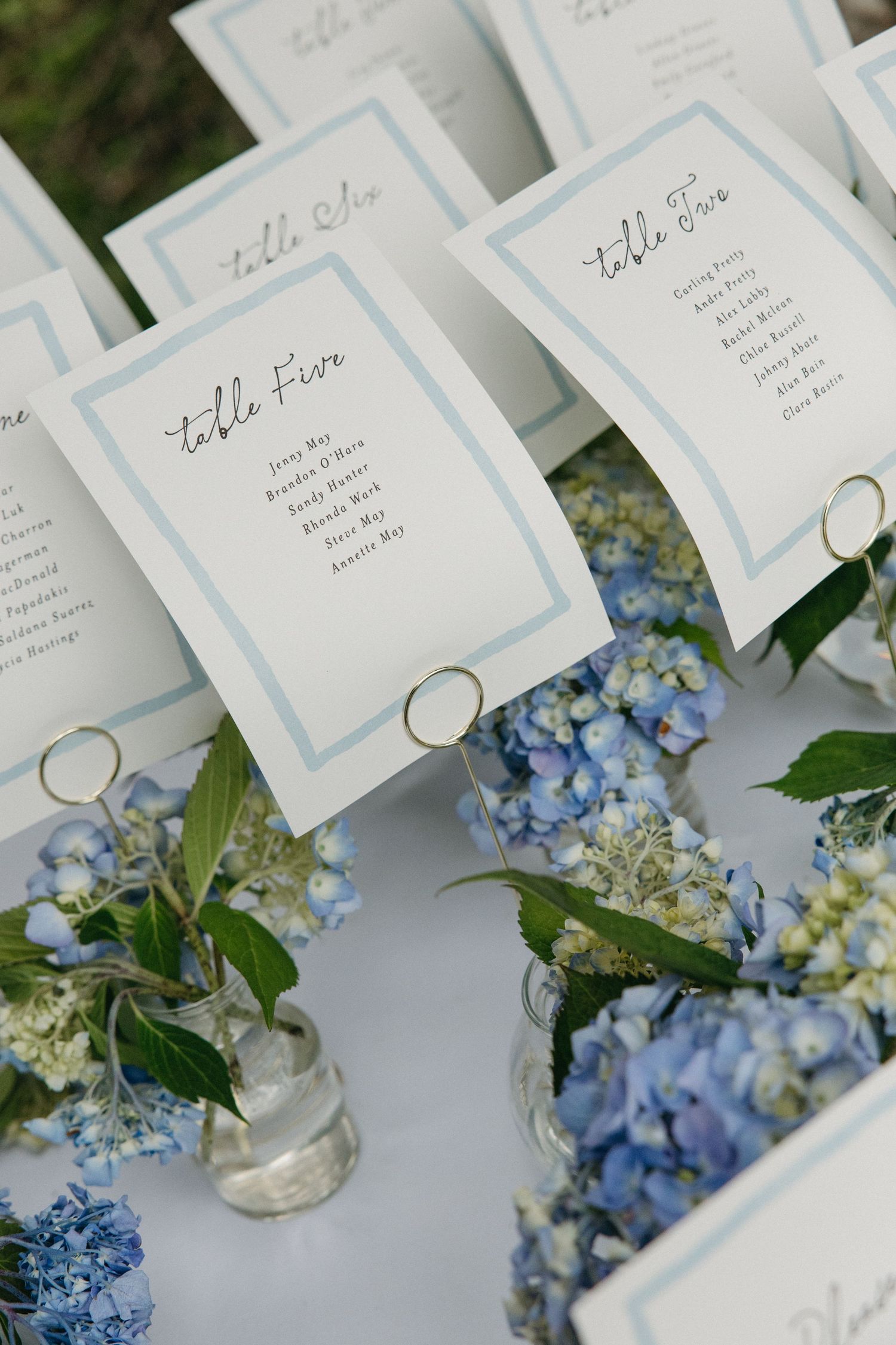 Blue hydrangea floral arrangements with elegant table seating cards at a wedding reception.