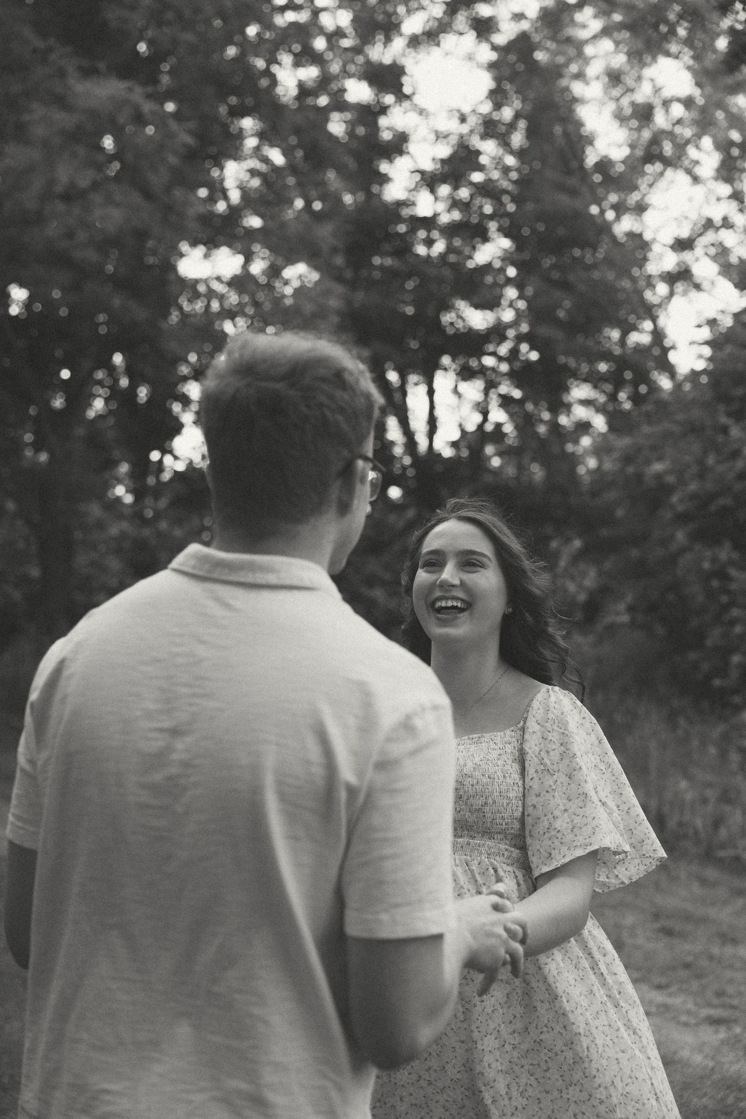 A candid moment captured between a couple laughing together in a natural outdoor setting.