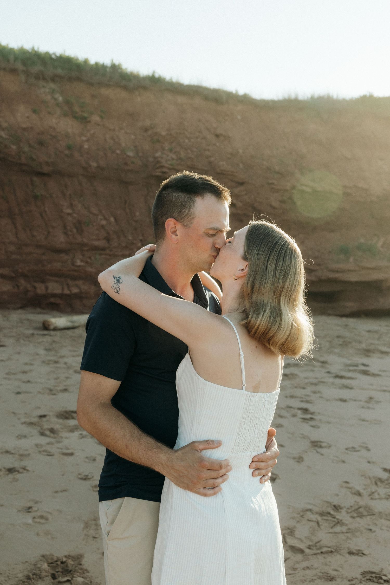 A romantic moment between a couple against red cliffs during sunset.