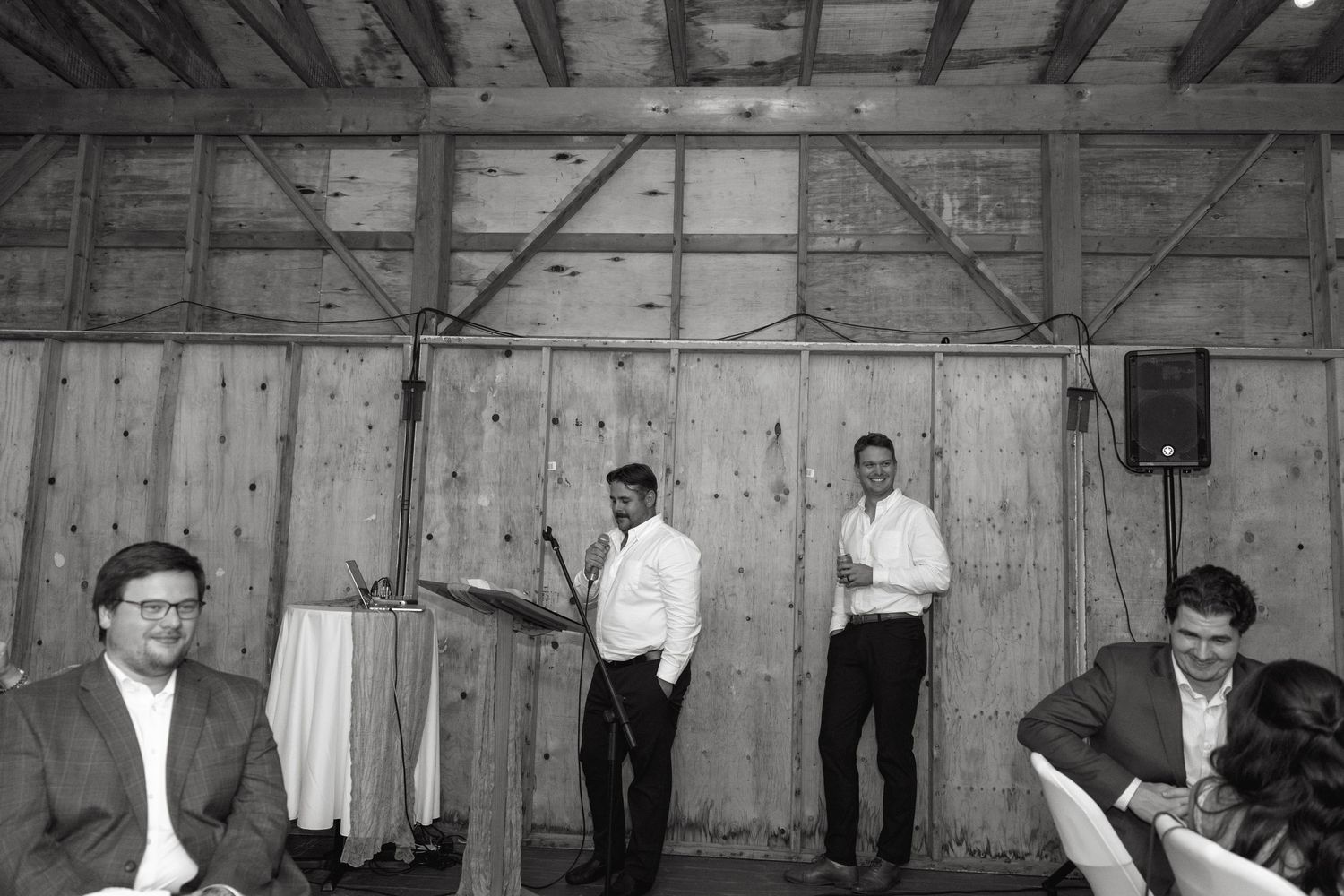 Rustic barn wedding reception with wooden beams and white draping.