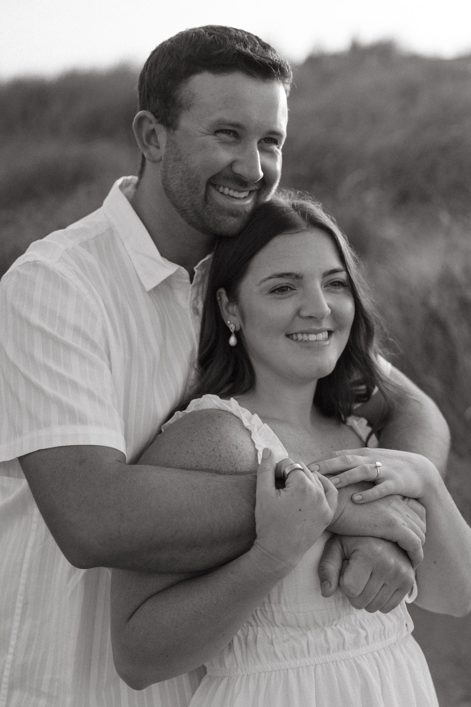 A joyful black and white portrait of a couple embracing outdoors.