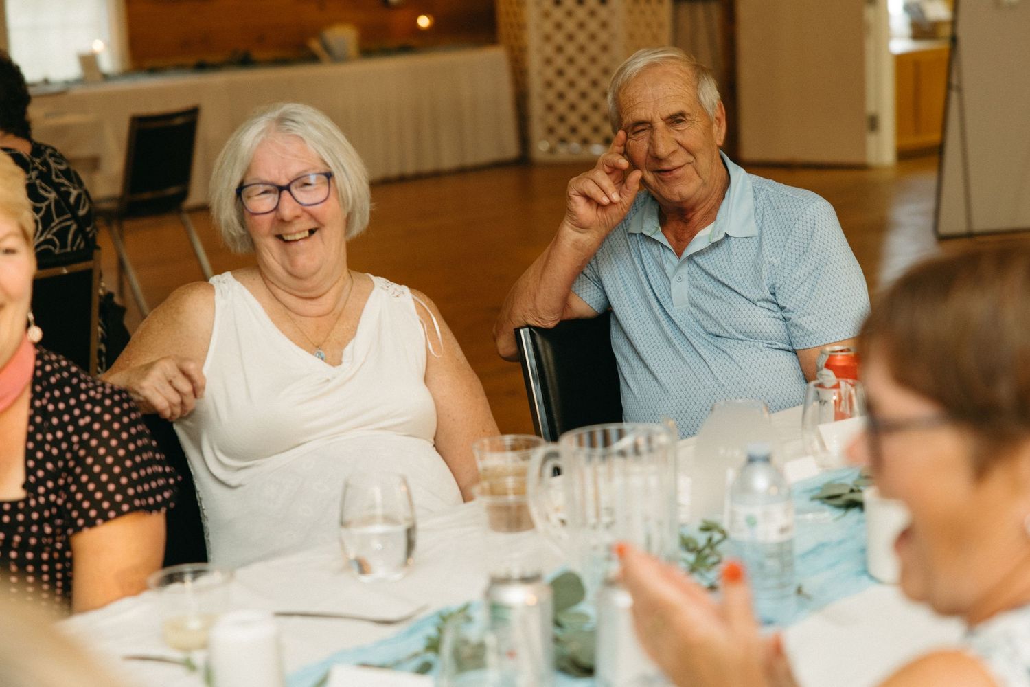 Wedding guests share laughter and conversation around an elegantly set dining table.