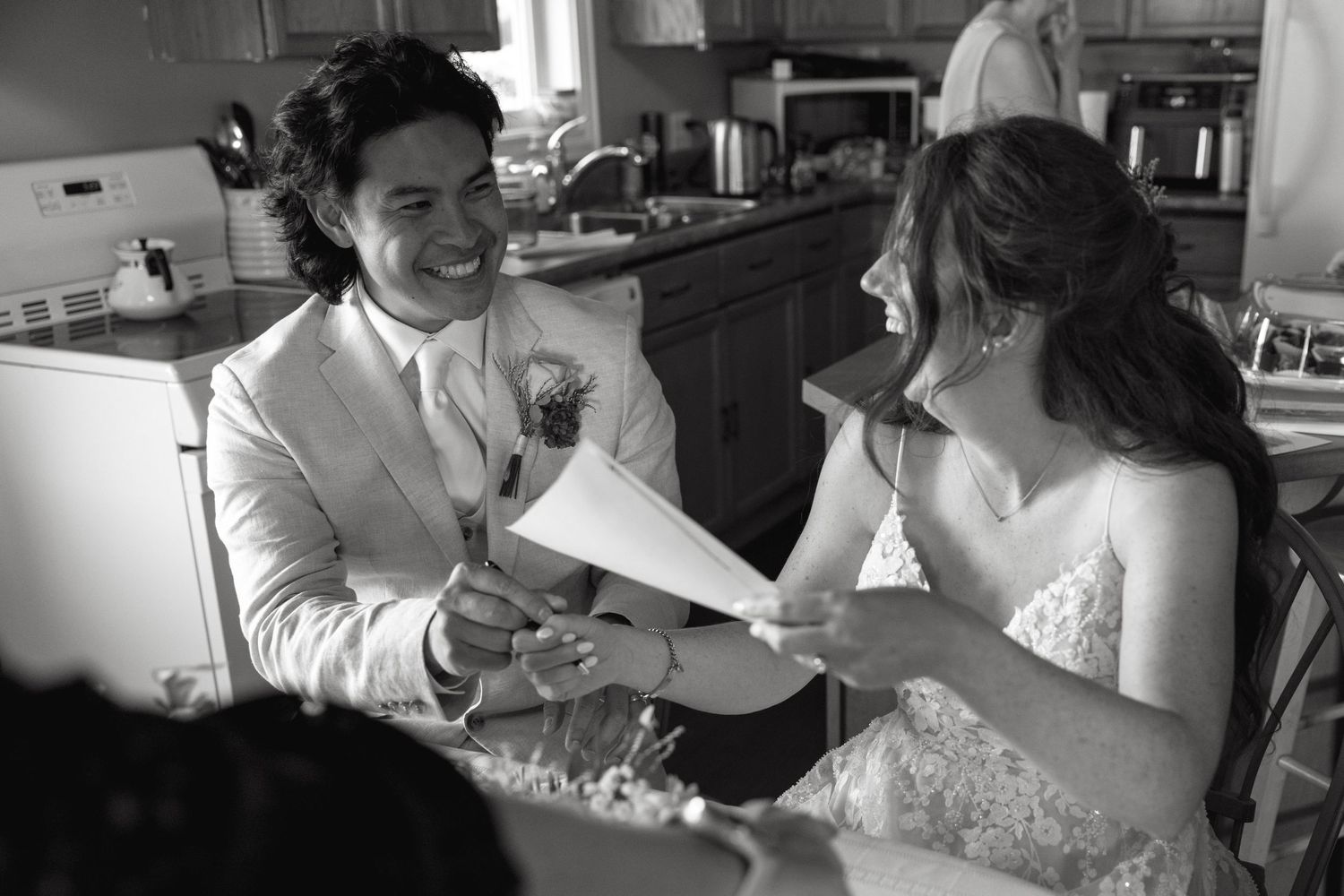 Black and white photo of couple sharing a lighthearted moment in the kitchen.
